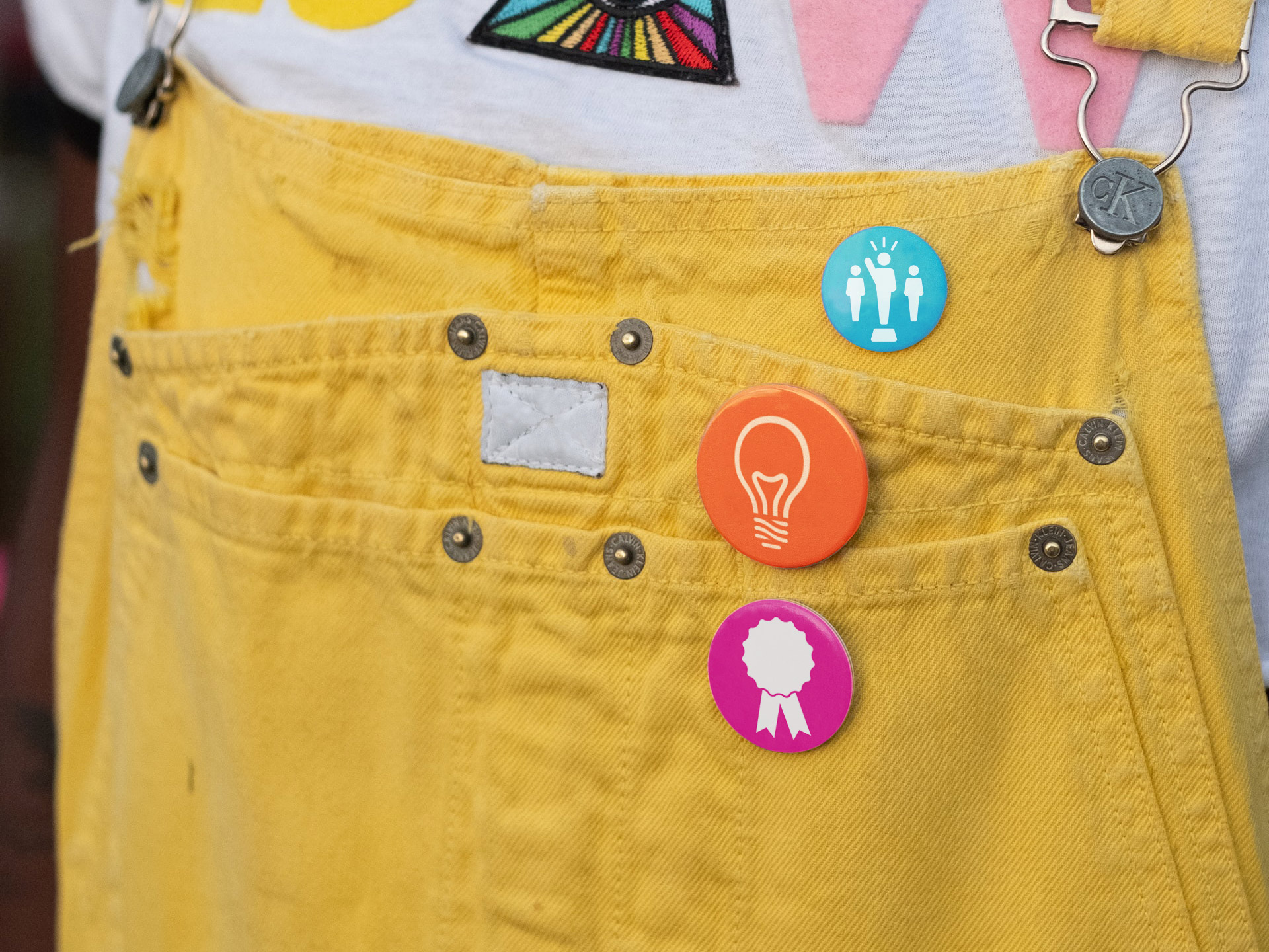 Ignite badges on a yellow denim overall